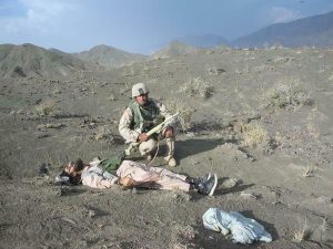 An unrelated leaked photo from the war: a US soldier poses with a dead Afghani man in the hills of Afghanistan